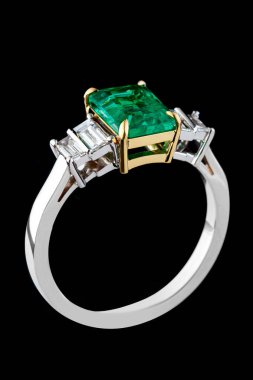 Zümrüt taşlı gümüş ya da altın yüzük ve yakın plan siyah zemin üzerinde elmaslar