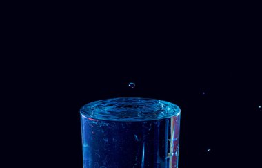 Su damlası düşüyor, makro sıçrama. Doğal ve karanlık bir arkaplanda yakın plan.