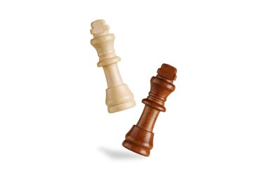Beyaz ahşap bir kral satranç taşının beyaz zeminde siyah bir papazın havada düşmesi. Strateji, zafer ve satranç temaları için ideal.