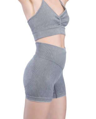 Gri kurdeleli atletik giysili bir kadının poposunun detaylı görüntüsü. Yüksek bel şort onun kıvrımlarını vurguluyor. Kumaşın tırtıklı dokusu açıkça görülüyor. Stüdyo ışıklandırması, beyaz arka plan. Spor kıyafetleri ve fitness reklamları için uygun. 