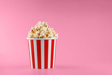 Kırmızı arka planda klasik kırmızı çizgili patlamış mısır karton bardak.