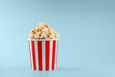 Mavi arka planda klasik kırmızı çizgili patlamış mısır karton bardak.