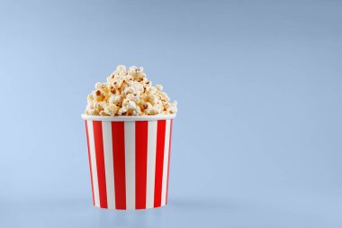 Mavi arka planda klasik kırmızı çizgili patlamış mısır karton bardak.