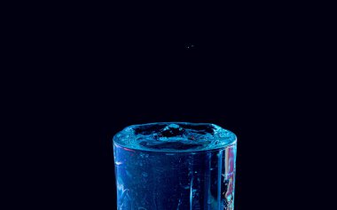 Su damlası düşüyor, makro sıçrama. Doğal ve karanlık bir arkaplanda yakın plan.