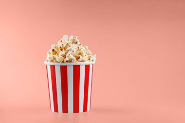 Turuncu arka planda klasik kırmızı çizgili patlamış mısır karton bardak.