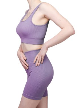 Formda bir kadının sırtından atölye çekiminde, gri çatallı, pürüzsüz spor şortu ve uyumlu spor sutyeni sergileniyor. Kumaş desenli bir örgü. Beyaz arka planda izole edilmiş. Spor giyim, spor giyim ve fitness programları için ideal.