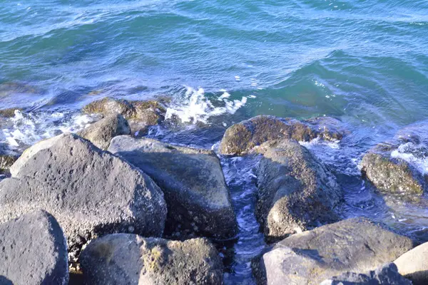 Sahilde kayalıklara vuran denizin göz kamaştırıcı sıçraması.