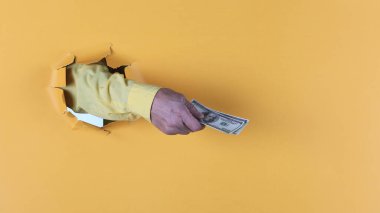 dollars in hand in a yellow paper hole