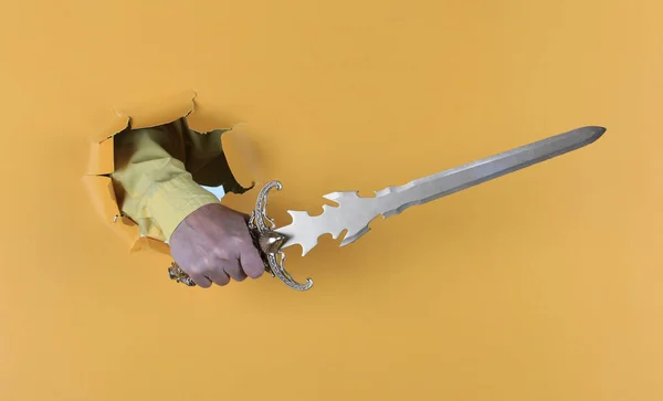sword in hand on yellow paper background