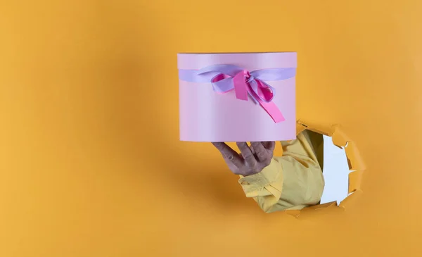 gift in hand on yellow paper background