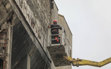 workers work on a construction hoist on the wall of a building