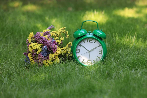 Bir Buket Yabani Çiçek Çimlerin Üzerinde Bir Çalar Saat — Stok fotoğraf