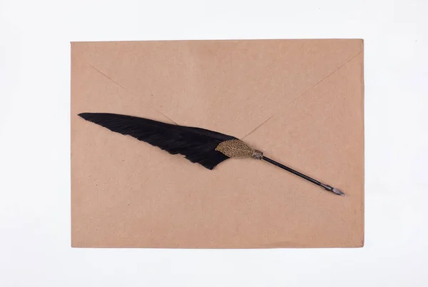 pen with a feather and an old brown paper envelope for writing
