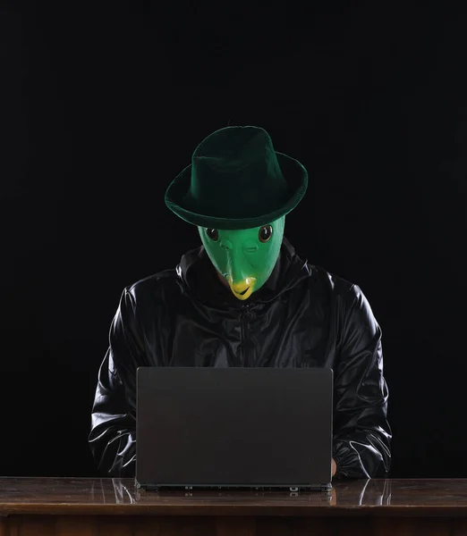 masked hacker with laptop at night
