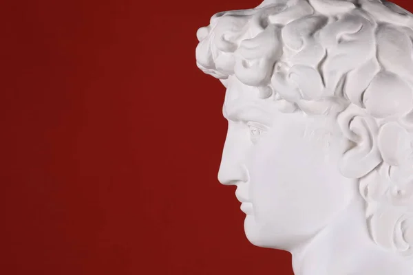 ancient white plaster head sculpture on a red background