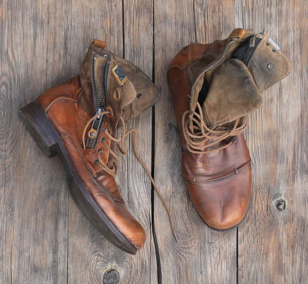 木製の背景に古い革の山のブーツ — ストック写真