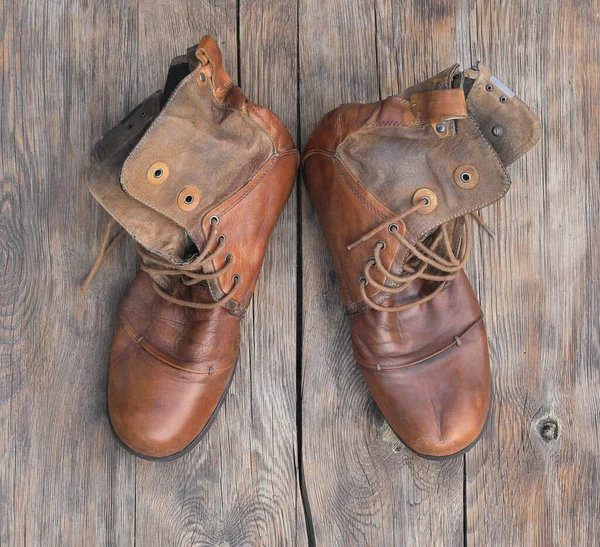 木製の背景に古い革の山のブーツ — ストック写真