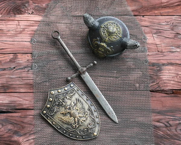 木製の背景に鉄鍛造盾と剣 — ストック写真