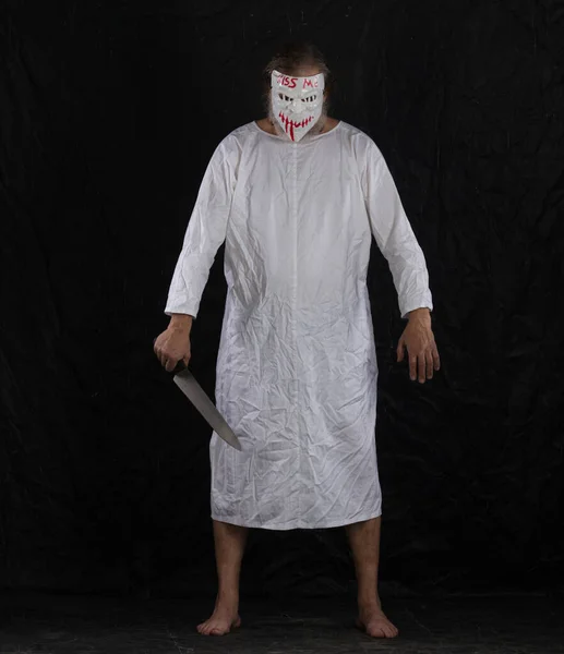 Stock image maniac in a hockey mask in a medical gown on a black background