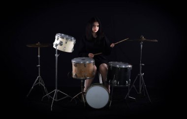 Kız siyah arka planda davul çalıyor.