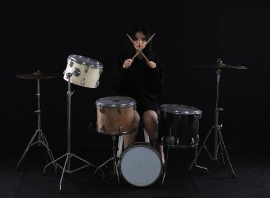 Kız siyah arka planda davul çalıyor.