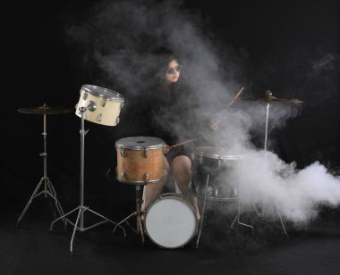 Kız siyah arka planda davul çalıyor.