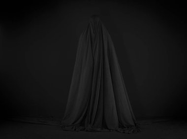 Siyah arka planda siyah pelerinli cadı