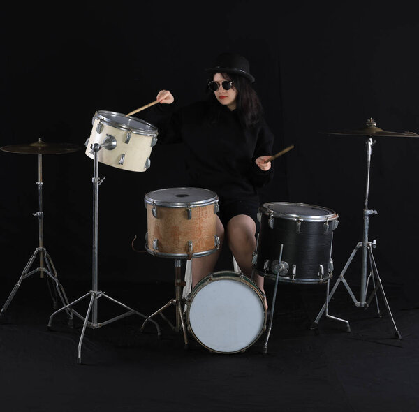 girl plays drums on a black background