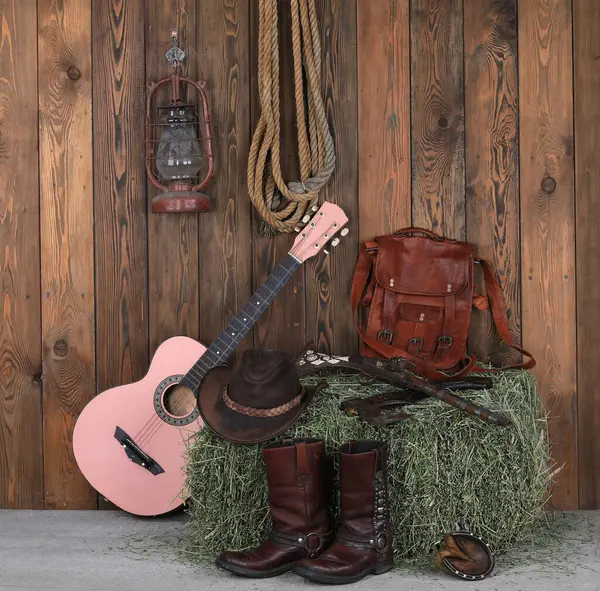 Gitar, kovboy çizmesi ve tahta zeminde silah.