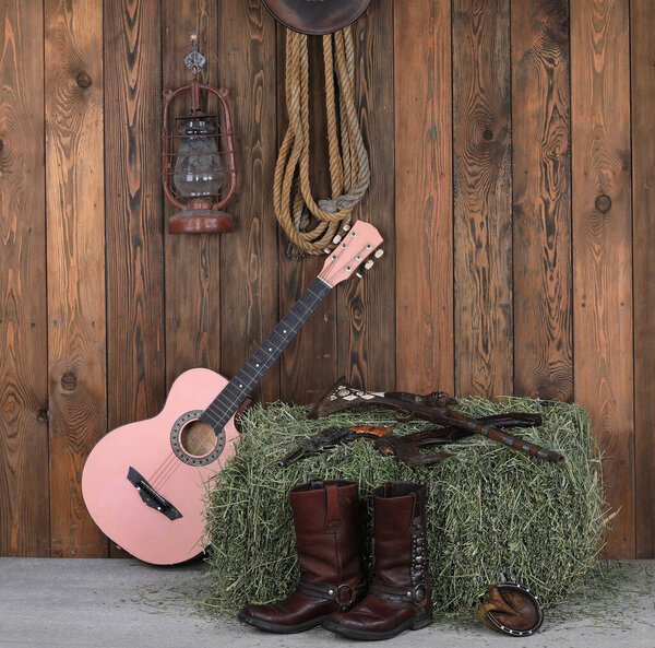 guitar, cowboy boots and gun on a wooden floor