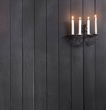 Siyah ahşap bir duvarda mum yakmak.
