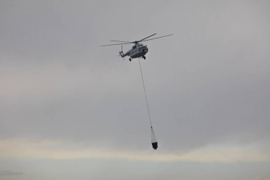 Helikopter, su sepetinden çıkan yangını söndürüyor.