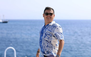 Asyalı zengin adam denizde dinleniyor.