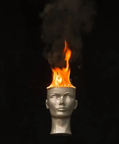 Fire on head.Mannequin head burns on a black background