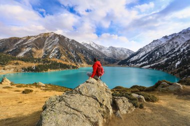 Kadın bir dağda, bir dağ gölünde, buzullarda duruyor. Büyük Almaty Gölü, Kazakistan, Almaty