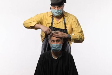 Beyaz arka planda tıbbi maskeli bir kuaförün portresi.