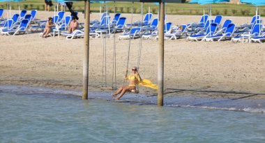 Bikinili kız sahilde sallanıyor.