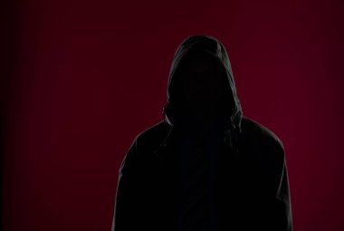 Siyah arka planda kapüşonlu bir adamın stüdyo portresi.