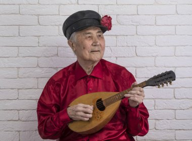 Rus adam telli müzik aleti çalıyor.