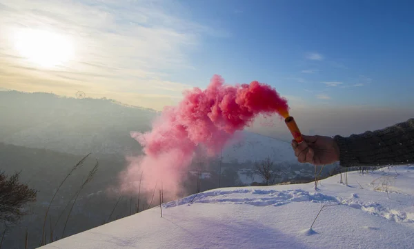 smoke bomb in hand with red smoke in winter mountains