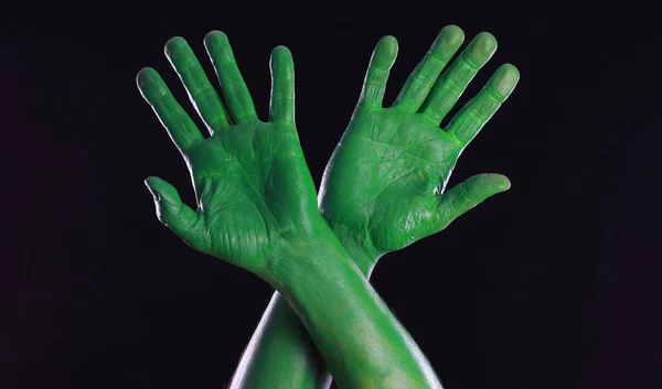green painted hands on black background