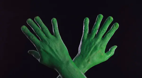 green painted hands on black background