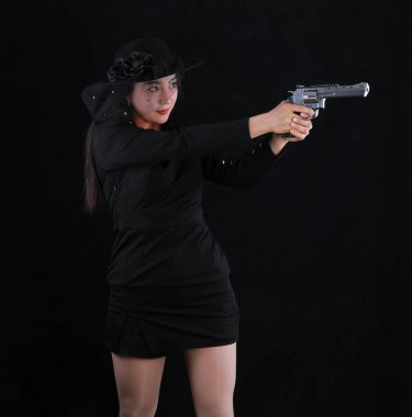 Siyah arka planda silahı olan seksi bir kız katilin portresi.