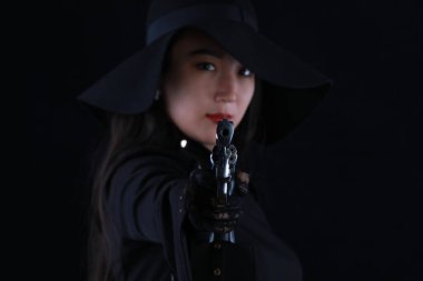 Siyah arka planda silahı olan seksi bir kız katilin portresi.