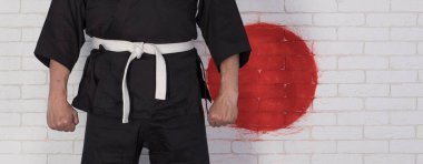 Siyah kuşaklı, beyaz kimonolu bir adam.