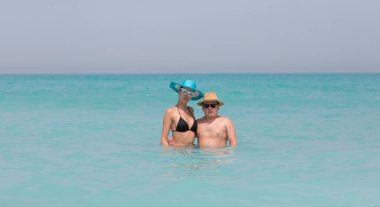 Erkek ve kız sahilde yüzüyorlar.