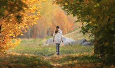 Genç kız sonbahar akçaağaç sokağında yürüyor.