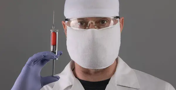 portrait of a male doctor in a mask with a syringe