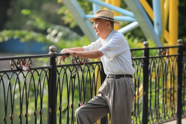 Yazın dışarıda dinlenen şapkalı yaşlı bir adam.