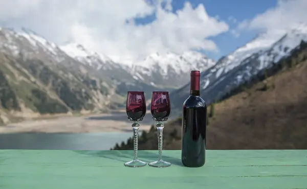 wine and glasses on the table in the mountains